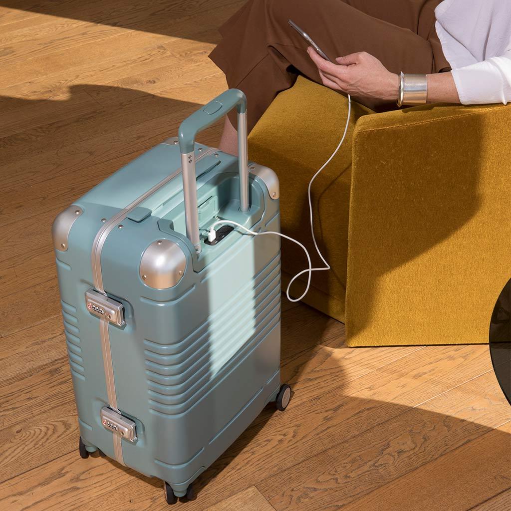 Woman charging her phone on the frame carry-on sage sight unseen collection.