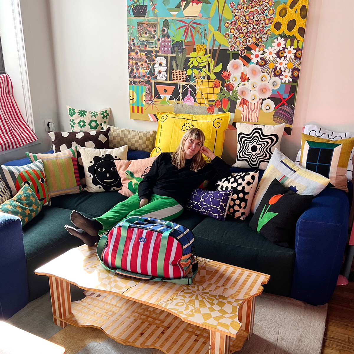 dusen dusen founder ellen van dusen sitting on sofa in her home with arlo skye x dusen dusen weekender featured sitting on coffee table in front of her