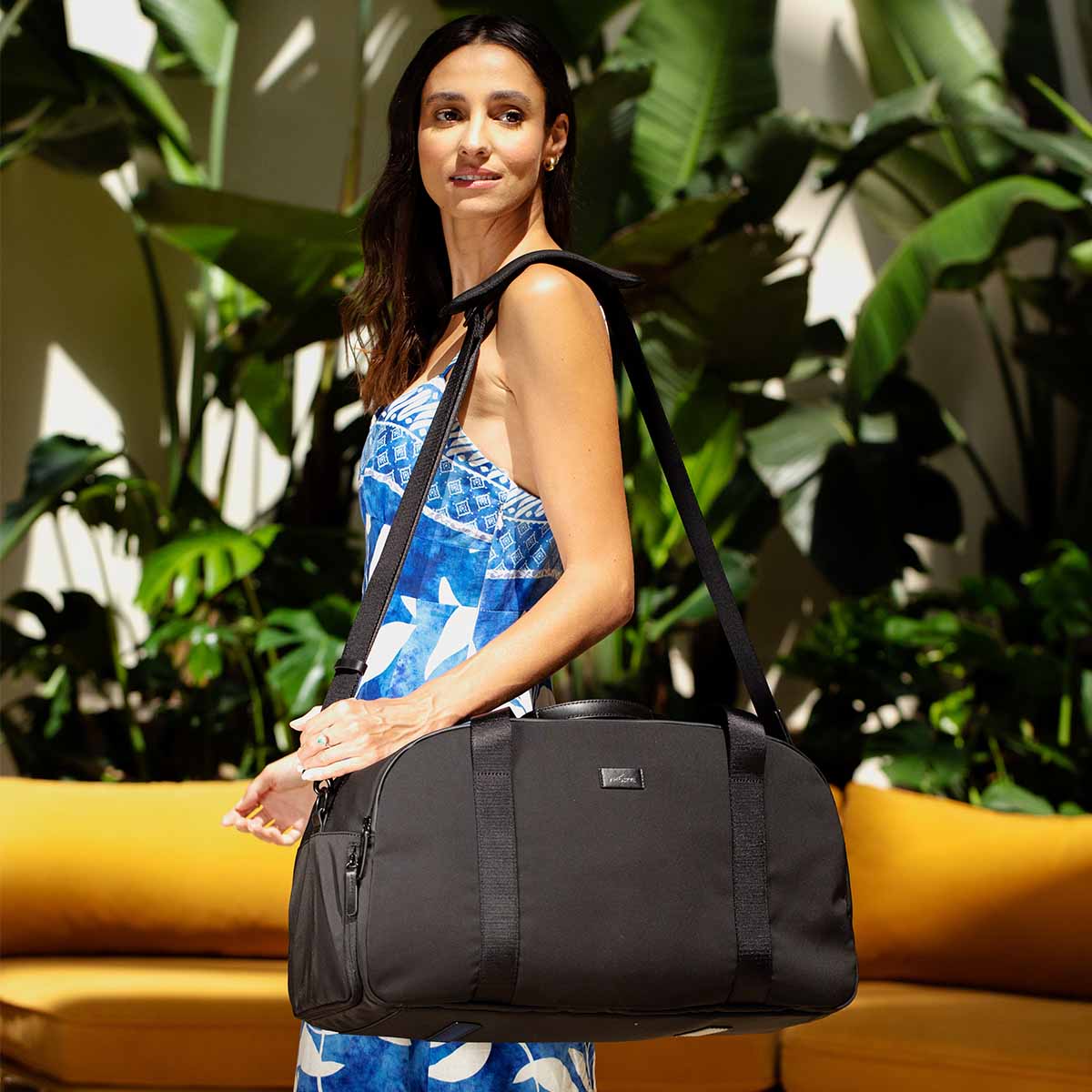 weekender in mint hanging on girl's left shoulder via shoulder strap.