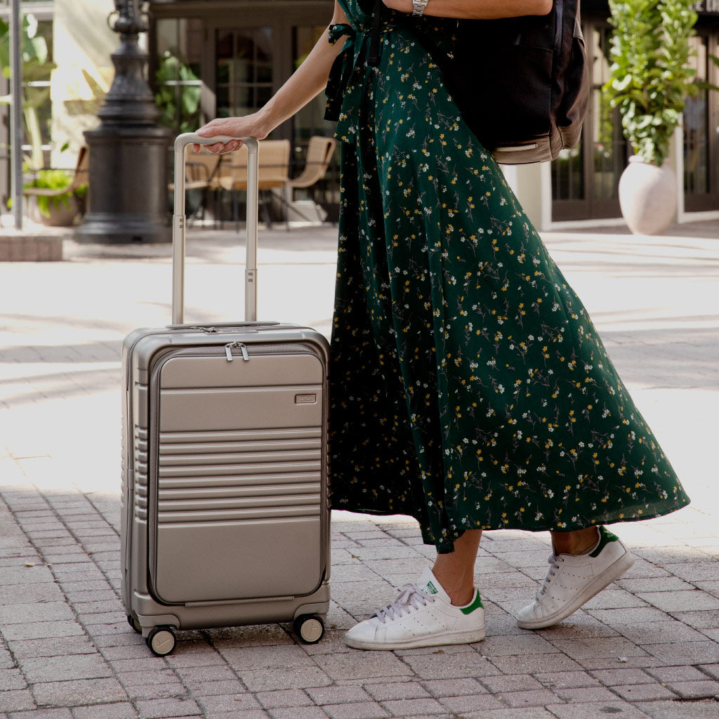 champagne carry-on max with front pocket being rolled on paved surface