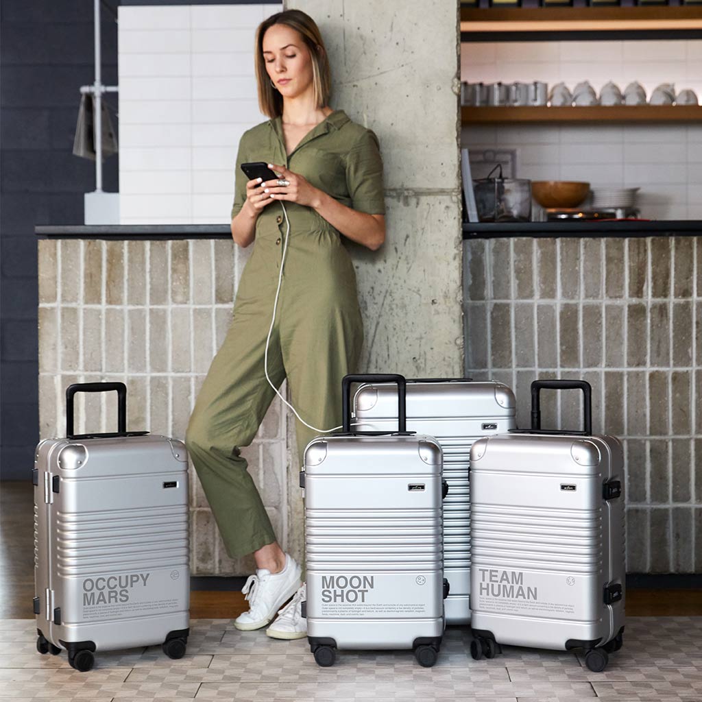 Woman charging her phone while traveling with the Arlo Skye Space Edition Collection.