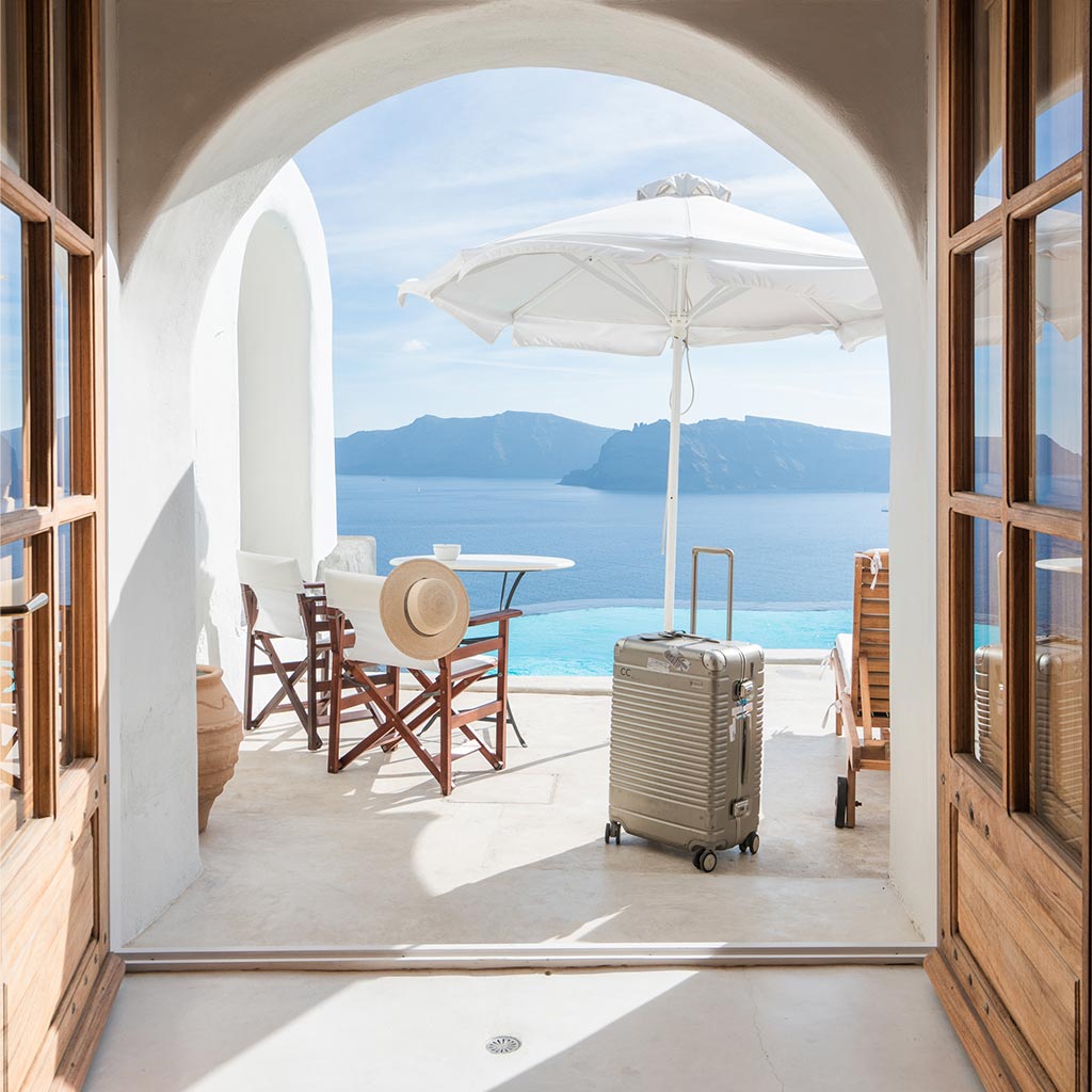 A hotel room in Greece with the Arlo Skye Check-In in Champagne Coloway visible in the balcony with water behind.
