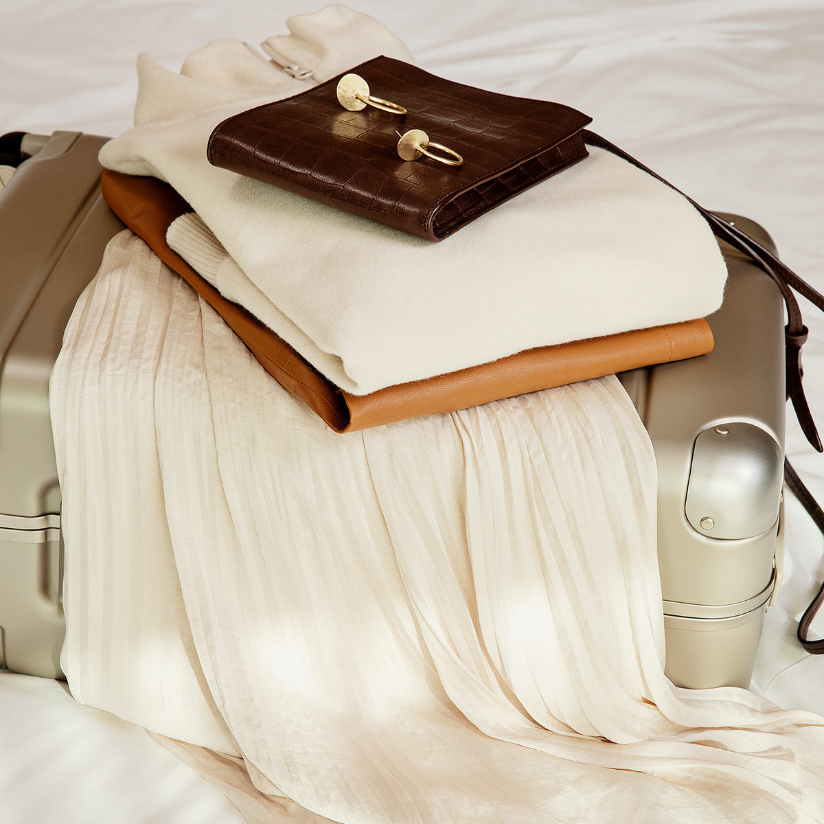 suitcase lying on bed with clothes on top.