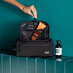 black travel kit with open top featuring some grooming products visible from the inside pockets.