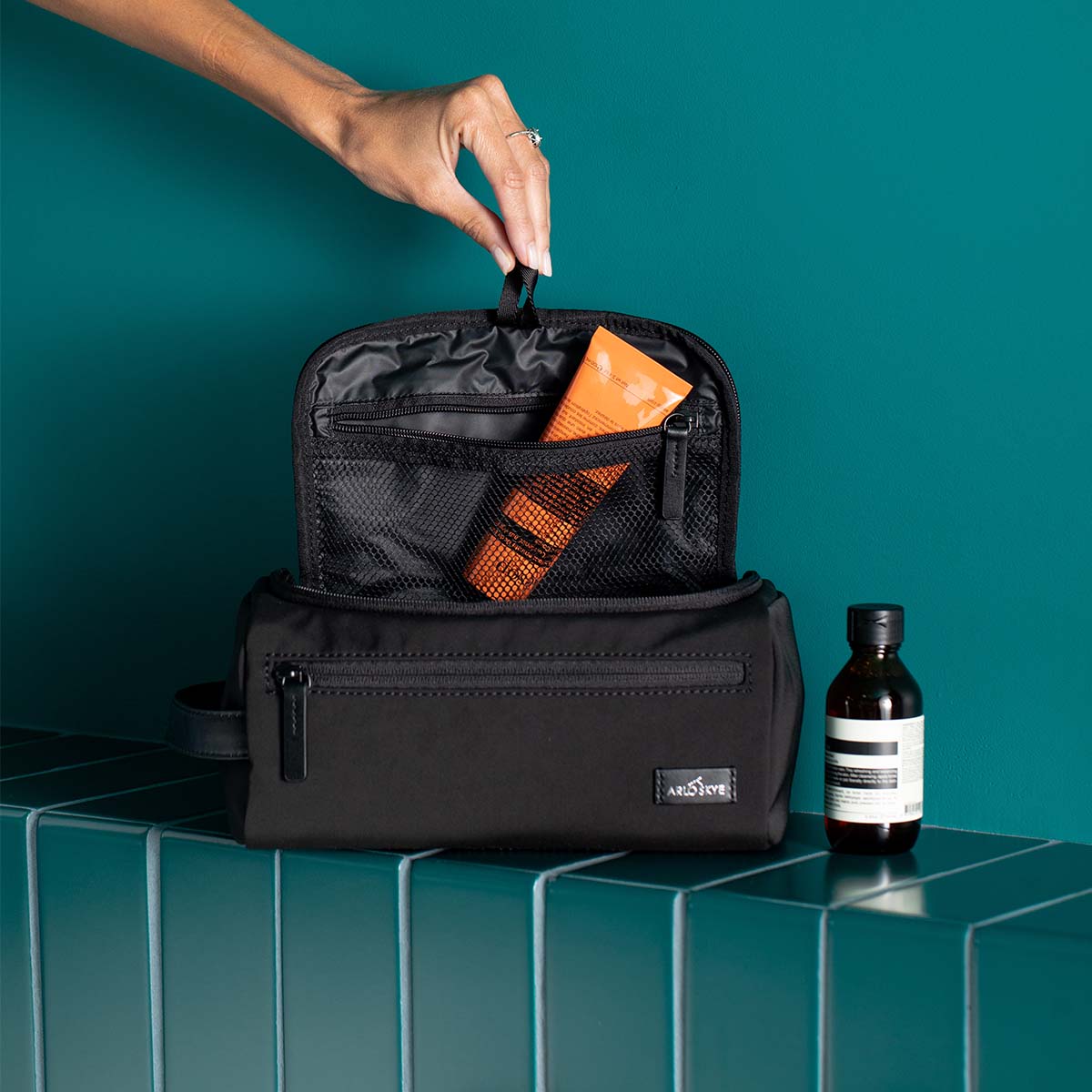 black travel kit with open top featuring some grooming products visible from the inside pockets.