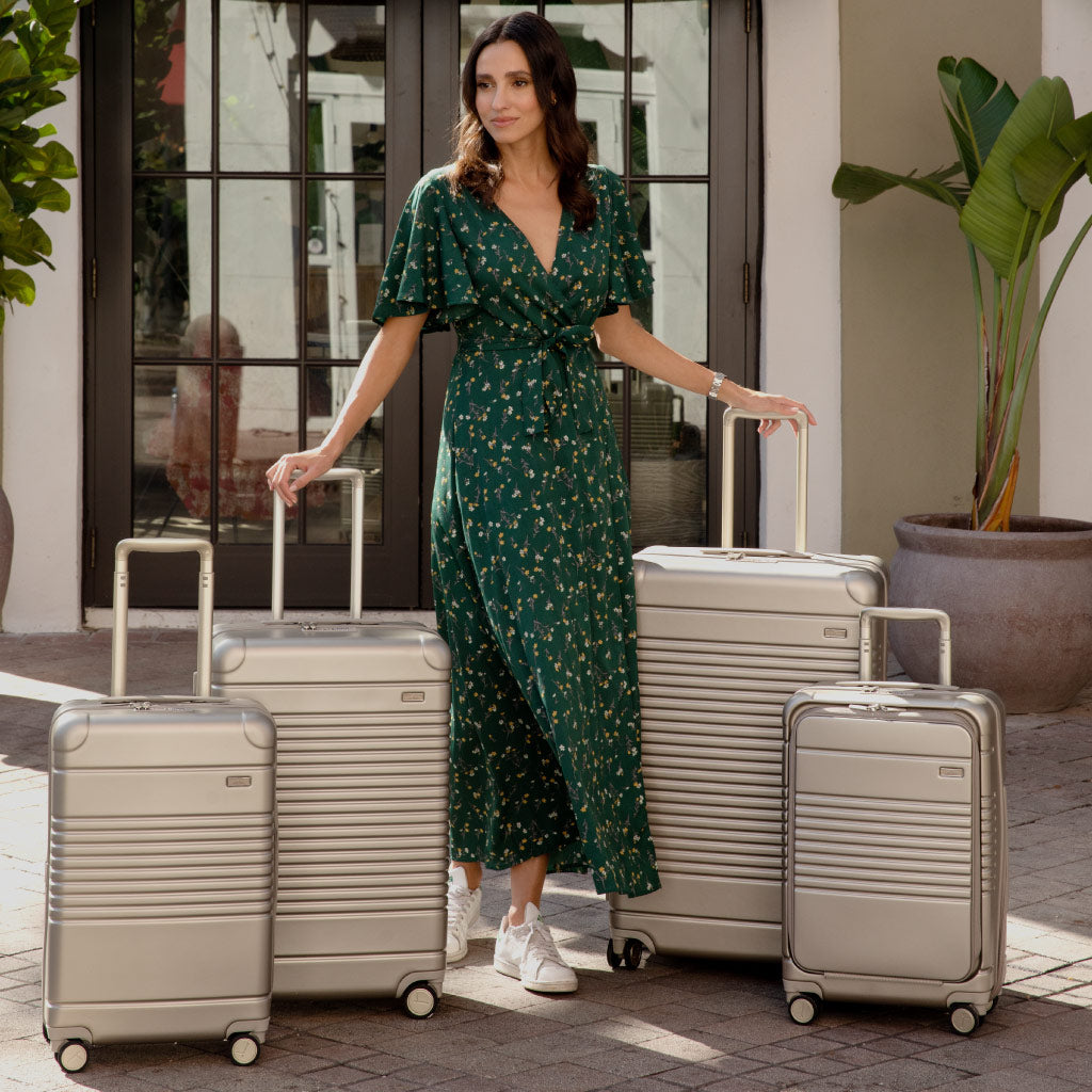 four zipper suitcases in champagne with model standing in middle.