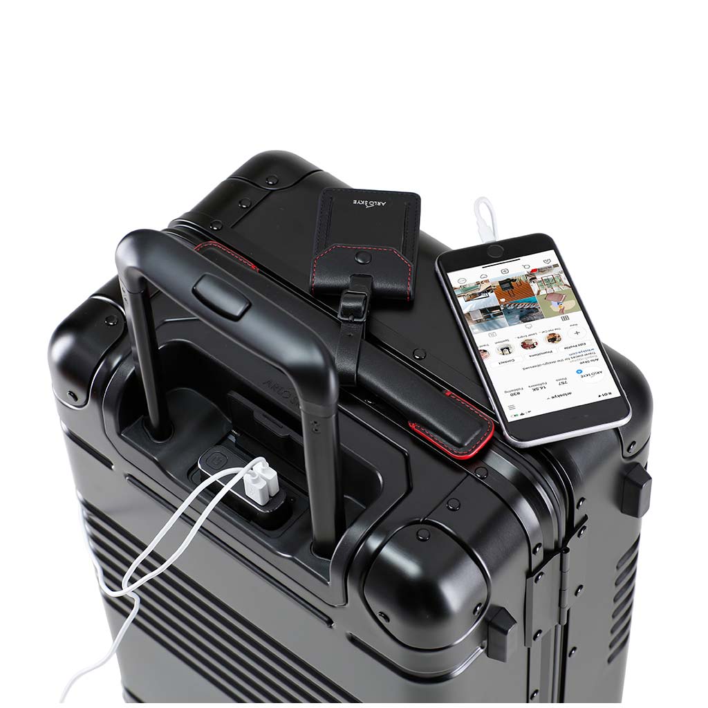 Top down view of the frame carry-on in black with red details aluminum edition and spare charger in use